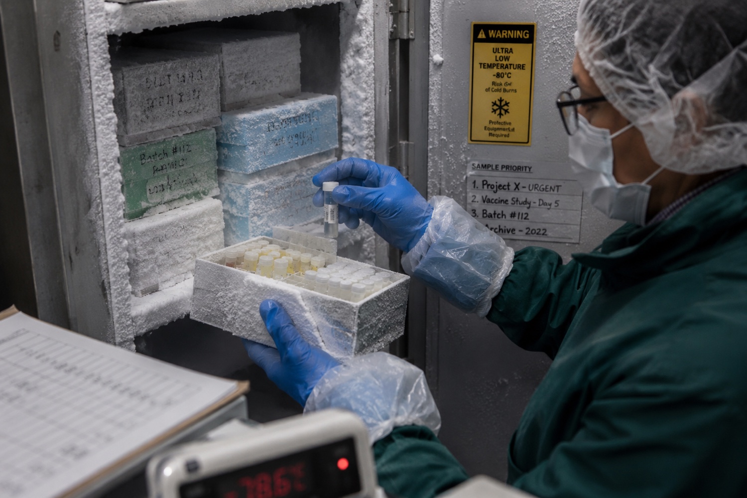 Lab worker handling labelled sample boxes in an ultra-low temperature freezer.